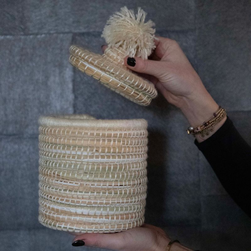 Interieurfoto van de handgemaakte raffia mand met pompondeksel, vervaardigd door vakmensen in Marokko, ideaal voor decoratie en praktische opslag.